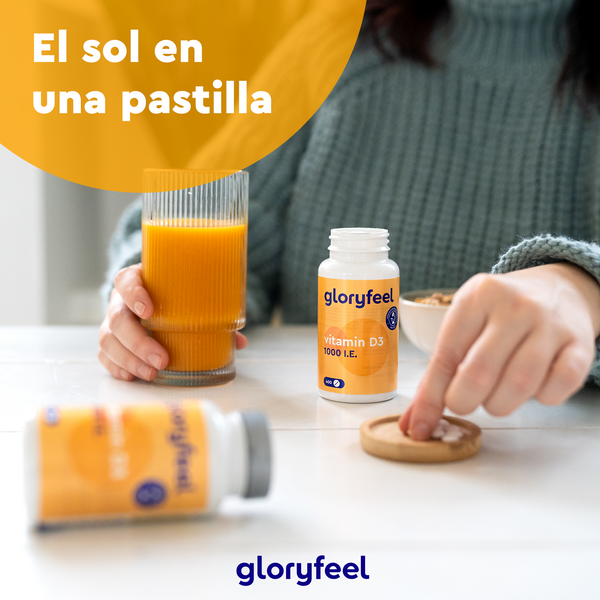 Una persona toma una tableta de Vitamina D3 1000 UI de una botella de GloryFeel GmbH España, junto a un zumo de naranja, con "El sol en una pastilla" encima, destacando los beneficios para unos huesos y dientes sanos.