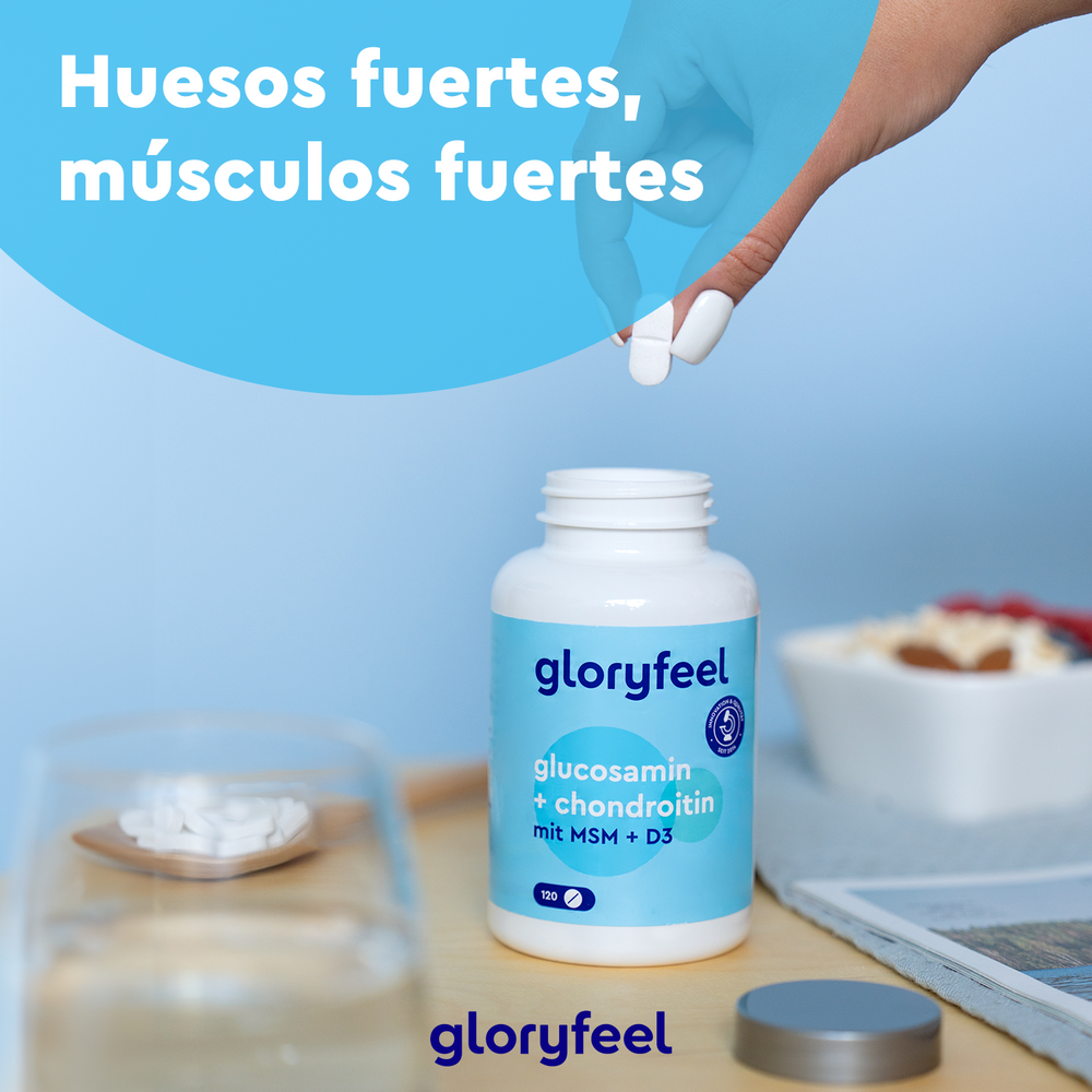 Una mano extrae pastillas de un frasco de suplementos de GloryFeel GmbH España con la etiqueta Glucosamina + Condroitina + MSM + Calcio y D3. La escena incluye una revista, un vaso de agua y un comedero. El texto dice: «Huesos fuertes, músculos fuertes».