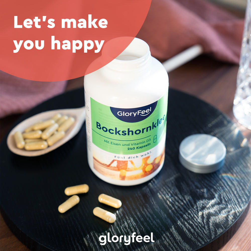Un frasco de gloryfeel GmbH Fenogreco 2.600 mg se encuentra en una bandeja negra con cápsulas esparcidas, la tapa quitada y un vaso de agua al lado.