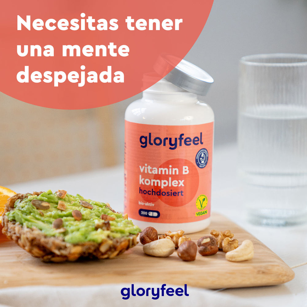 Una botella de Vitamina B Complex Forte de GloryFeel GmbH España se encuentra junto a una tostada de aguacate, frutos secos y agua. El texto &quot;Necesitas tener una mente despejada&quot; destaca cómo estos nutrientes esenciales favorecen tu metabolismo y te mantienen alerta a diario.