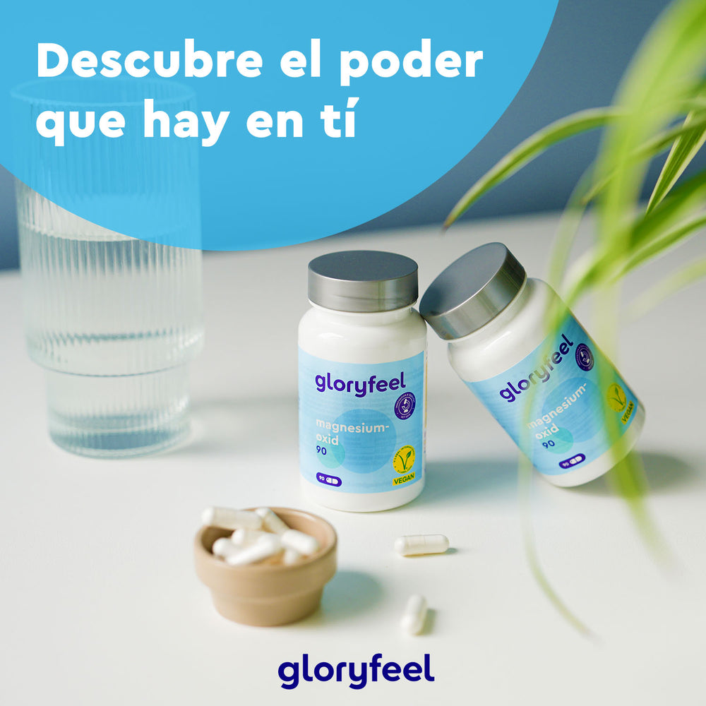 Se muestran dos botellas de Magnesio 90 Cápsulas Veganas de Gloryfeel GmbH junto a un vaso de agua, un pequeño recipiente con cápsulas y una planta. El texto en español dice: «Descubre el poder que hay en ti con magnesio».