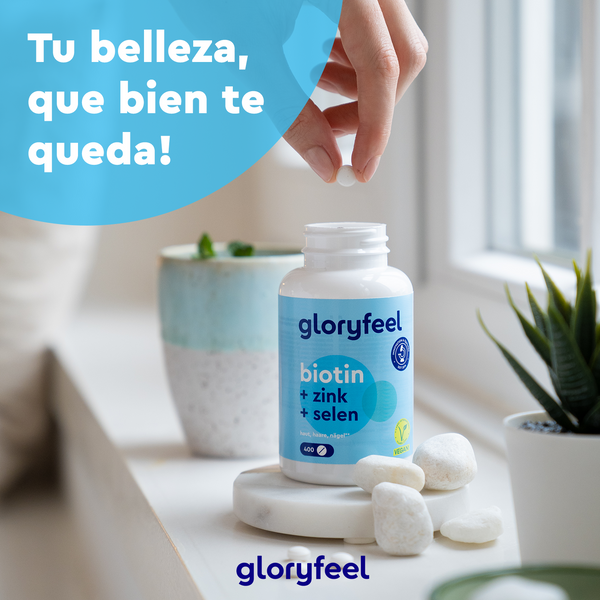 Una mano alcanza un frasco de Biotina en tabletas de GloryFeel GmbH España en el alféizar de una ventana, rodeado de plantas y piedras. El texto dice &quot;¡Tu belleza, que bien te queda!&quot;. Mejora la salud de tu cabello de forma natural.