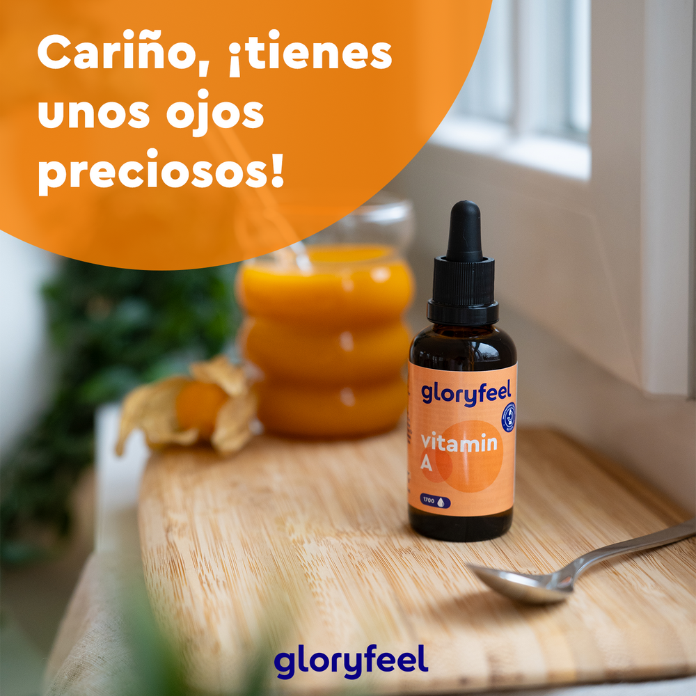 Una botella de Vitamina A en gotas con palmitato de retinilo de GloryFeel GmbH (España) reposa sobre una superficie de madera junto a una cuchara, rodeada de un vaso de zumo de naranja y physalis. Un círculo naranja con texto flota sobre la escena.
