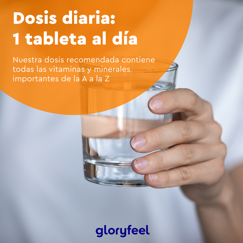 Una mano sostiene un vaso de agua con un texto en español que promociona comprimidos multivitamínicos veganos ricos en antioxidantes y vitaminas esenciales de la A a la Z. La marca &quot;GloryFeel GmbH España&quot; se muestra en la parte inferior.