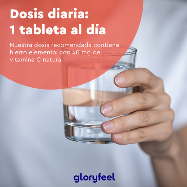 Una mano sostiene un vaso de agua transparente con un texto en español sobre la dosis diaria de una tableta natural de Hierro + Vitamina C de GloryFeel GmbH España.