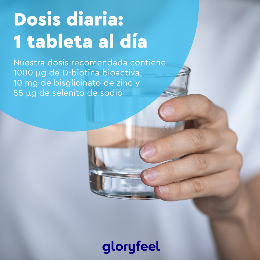 Una mano sostiene un vaso de agua junto a un texto en español sobre la dosis diaria de las tabletas y sus ingredientes, como la biotina. Ideal para quienes buscan mejorar la salud capilar con suplementos alimenticios como &quot;Biotina en tabletas&quot; de GloryFeel GmbH España.
