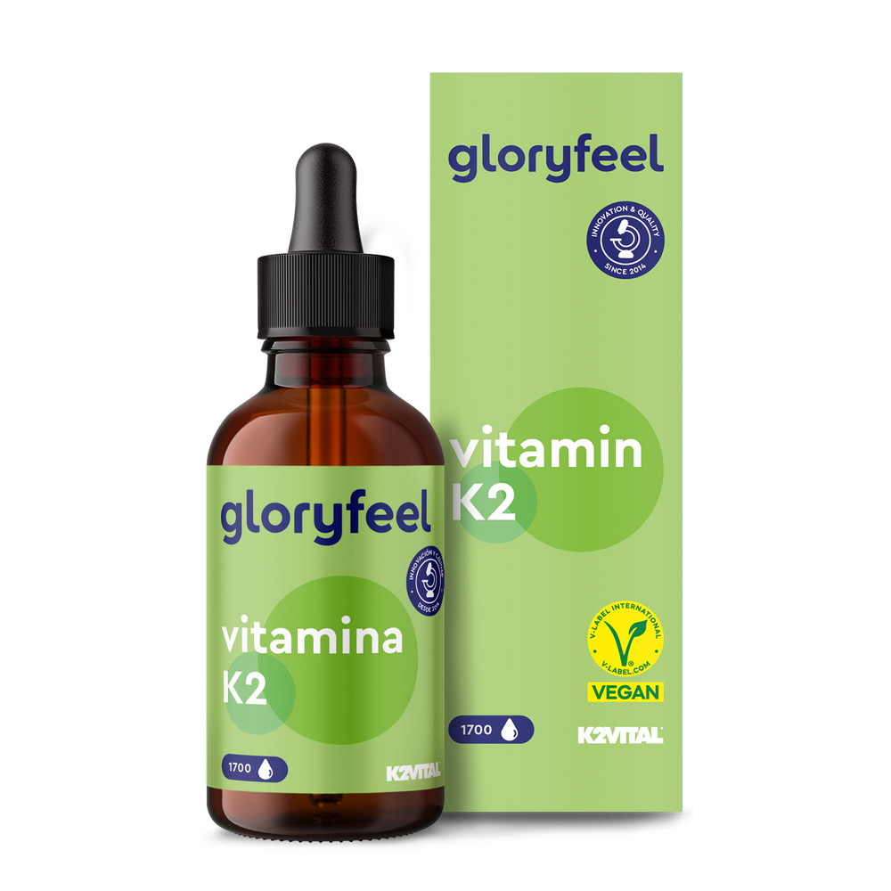 Un frasco de Vitamina K2 Gotas de GloryFeel GmbH España, vital para la coagulación sanguínea y la formación de huesos, incluye un gotero y está envasado en un embalaje vegano verde etiquetado como &quot;1700 gotas&quot;.