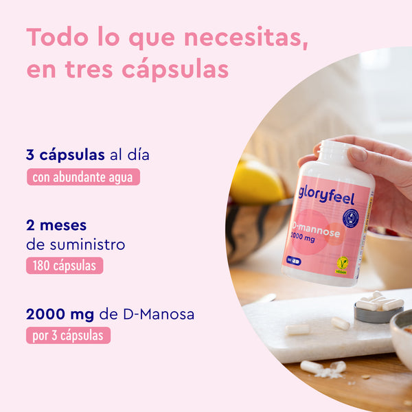 Una botella de cápsulas de D-Manosa - 2.000 mg por día de gloryfeel GmbH se sostiene en una mano contra un fondo de mesa de madera, lo que sugiere una dosis de 3 cápsulas diarias para apoyar las vías urinarias, con suministro suficiente para 2 meses.