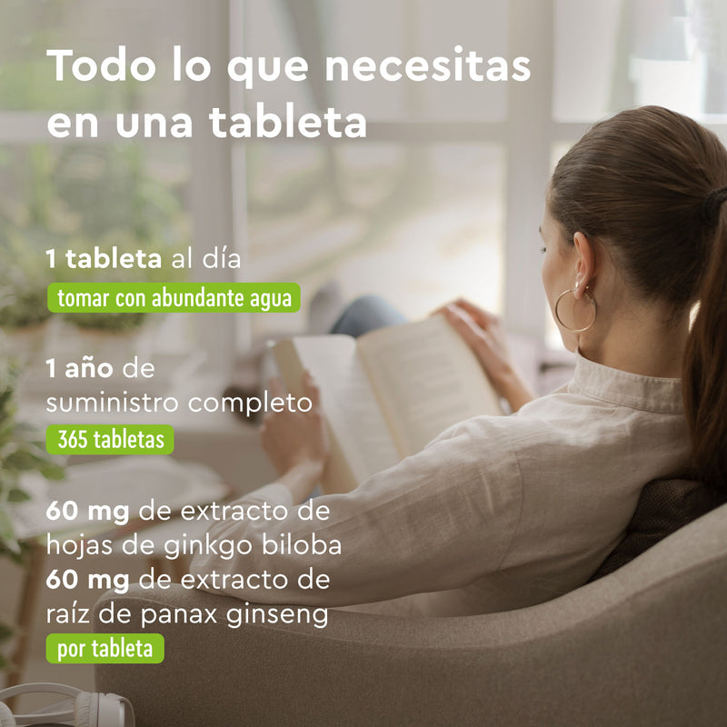 Una mujer está sentada junto a la ventana, absorta en su libro desde el sofá. A su lado, un texto sobre las Tabletas de Ginkgo Ginseng de gloryfeel GmbH España, una tableta diaria enriquecida con ginkgo biloba —un producto básico en la medicina tradicional china— que se toma con agua. Un suministro anual de 365 tabletas garantiza que nunca te pierdas sus beneficios.