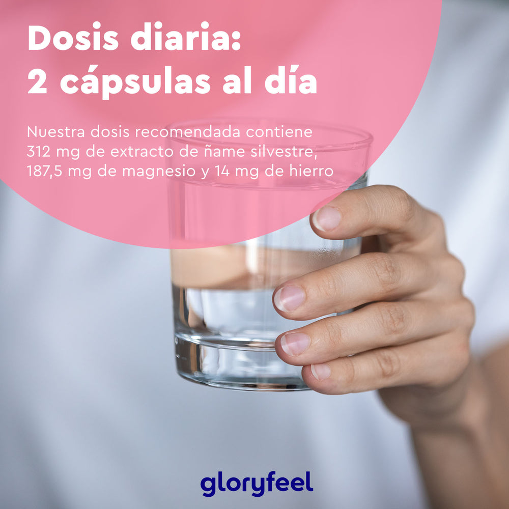 Una mano sostiene un vaso de agua con un texto en español que recomienda tomar dos cápsulas veganas diarias de gloryfeel GmbH, cada una con 312 mg de extracto de ñame silvestre enriquecido con diosgenina de ñame silvestre, además de 187,5 mg de magnesio y 14 mg de hierro para una salud óptima.