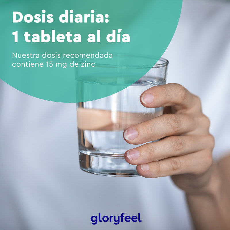 Una mano sostiene un vaso de agua con texto en español sobre la dosis diaria de Zinc 15 mg - 400 tabletas de Gloryfeel GmbH, enfatizando el gluconato de zinc para mejorar su sistema inmunológico.